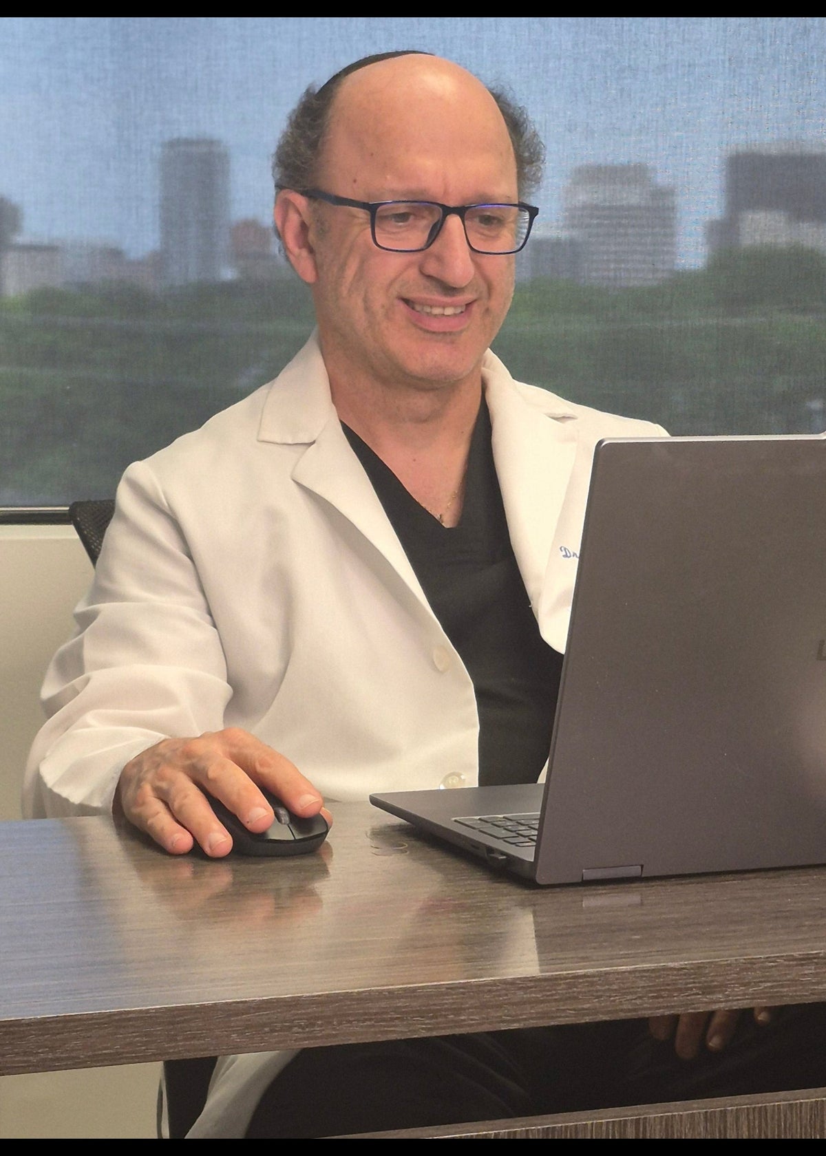 Man taking a selfie with a laptop on a desk in an office setting