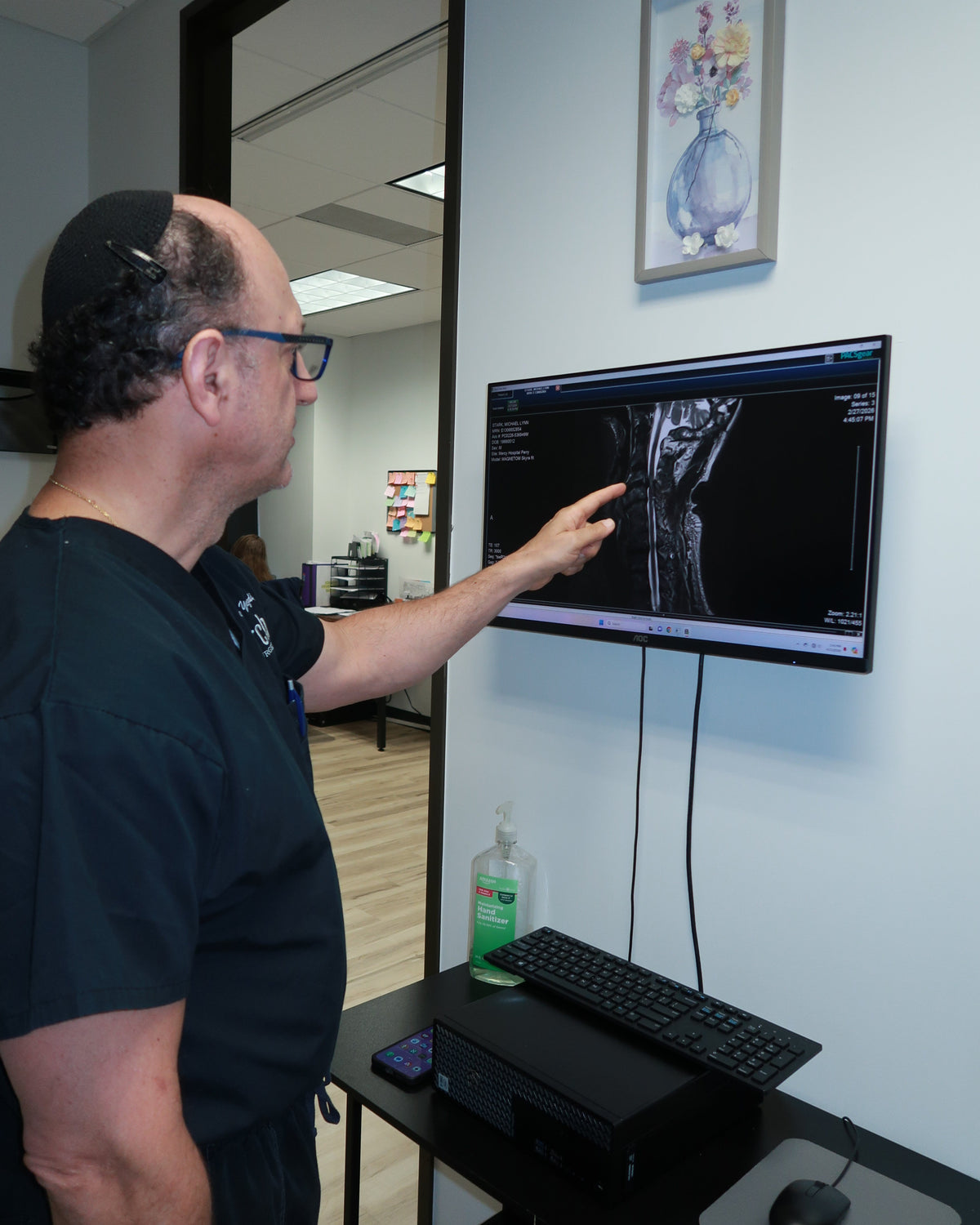Person interacting with a computer screen displaying an ultrasound image in a medical setting.