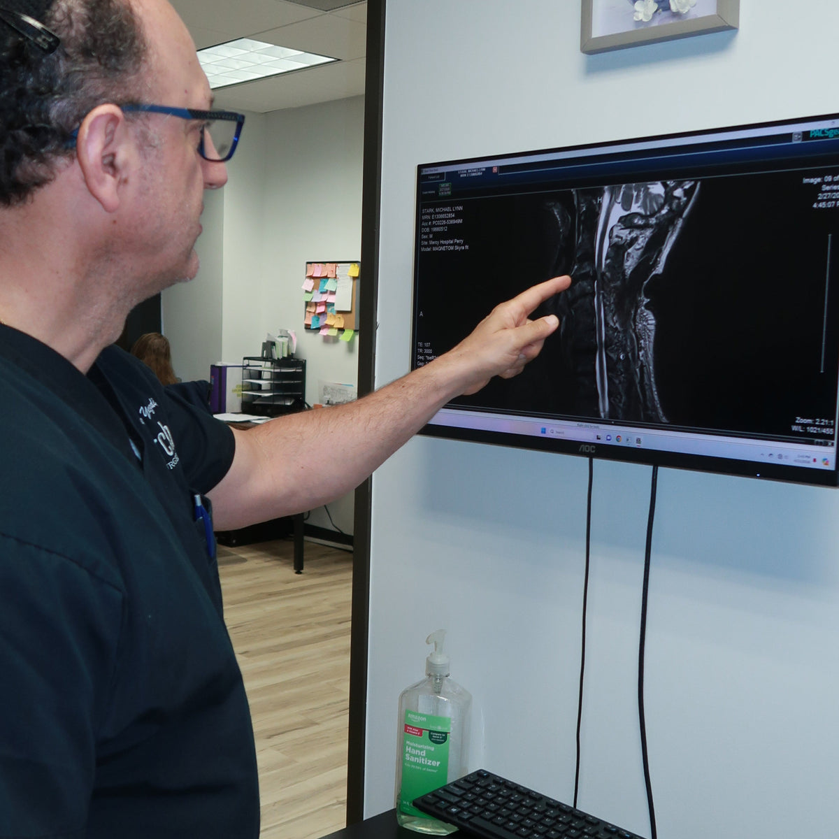 Person interacting with a computer screen displaying an ultrasound image in a medical setting.